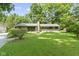 Charming single-story home with a well-maintained lawn, beautiful trees and a yellow front door at 6430 N Rural St, Indianapolis, IN 46220