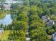 Aerial shot showcasing a green corridor alongside houses, with a pond and commercial buildings in the background at 8835 Harrison Pkwy, Fishers, IN 46038