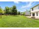 Large, grassy backyard enclosed by a wooden fence, featuring a patio and fire pit for outdoor enjoyment at 8835 Harrison Pkwy, Fishers, IN 46038