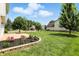 Backyard featuring a lush lawn, trees, and a brick patio with flowers at 8835 Harrison Pkwy, Fishers, IN 46038