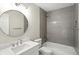Bright bathroom with a round mirror over a white vanity and tiled shower-over-tub at 8835 Harrison Pkwy, Fishers, IN 46038