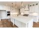 Bright kitchen with white cabinets, a large island, modern appliances, and hardwood flooring at 10201 - Lot 2 N Alford Rd, Fortville, IN 46040
