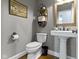Stylish powder room with pedestal sink, dark fixtures, shelving and modern finishes at 111 N 8Th St, Zionsville, IN 46077