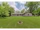 A lush backyard, surrounded by mature trees, and a fire pit is perfect for gatherings at 11230 N College Ave, Carmel, IN 46032