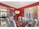 Elegant dining room with seating for six, with glass top, stylish light fixture and red accent wall at 11995 Gray Eagle Dr, Fishers, IN 46037