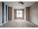 Spacious bedroom featuring a ceiling fan, large window, neutral carpeting, and blue striped accent wall at 1418 Blackthorne S Trl, Plainfield, IN 46168