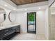 Modern bathroom featuring black vanity with marble countertop, dual sinks, wood ceiling, and door to private deck at 1805 Wood Valley Dr, Carmel, IN 46032