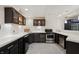 Basement kitchenette features dark cabinets, stainless steel appliances, and stylish flooring at 1805 Wood Valley Dr, Carmel, IN 46032