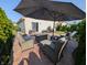 Rear patio features an umbrella, wicker furniture and beautiful landscaping for outdoor enjoyment at 1823 Long Lake Dr, Greenwood, IN 46143