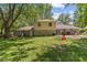 Spacious backyard featuring mature trees and the exterior of the home with stone accents at 1930 Bechtel Rd, Indianapolis, IN 46260