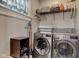 A functional laundry room with shelving, a window, and modern washer and dryer at 2332 Central Ave, Indianapolis, IN 46205