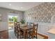 Dining room featuring a rustic wooden table, seating for eight, decorative wallpaper, and sliding door access to the deck at 3679 Woodruff Pl, Bargersville, IN 46106