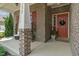 Inviting front porch with brick columns, potted plants, and a cozy seating area and a red front door at 3679 Woodruff Pl, Bargersville, IN 46106