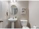 A powder room with a pedestal sink, toilet, round mirror, and neutral wall color at 3679 Woodruff Pl, Bargersville, IN 46106
