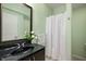 Bright bathroom with a sleek black vanity, modern fixtures, and a shower with a white curtain at 3853 Abney Highland Dr, Zionsville, IN 46077