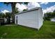 View of a detached garage with vinyl siding and an entry door, surrounded by a green yard at 4639 Terrace Ave, Indianapolis, IN 46203