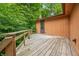 Back deck area with wooden plank floor and railing, surrounded by trees at 5052 Helmsburg School Rd, Morgantown, IN 46160