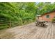 Wooden deck with picnic table overlooking lush greenery offers a scenic outdoor space for dining and relaxation at 5052 Helmsburg School Rd, Morgantown, IN 46160
