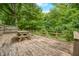A spacious, wooden deck with picnic table offers an outdoor retreat surrounded by lush greenery and a partial railing at 5052 Helmsburg School Rd, Morgantown, IN 46160