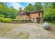 Charming tan home with a screened porch, gravel driveway, propane tank, and yard art surrounded by lush trees at 5052 Helmsburg School Rd, Morgantown, IN 46160
