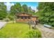Quaint tan home with screened porch, gravel driveway, yard art, and wooded backdrop is inviting and serene at 5052 Helmsburg School Rd, Morgantown, IN 46160
