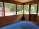 Relaxing enclosed porch with wood paneling, an exterior view of wooded area, and carpeted floor at 5052 Helmsburg School Rd, Morgantown, IN 46160