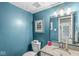 Bathroom featuring blue walls, decorative mirror, granite countertop, and white fixtures at 5299 Breakers Way, Carmel, IN 46033