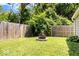 Backyard view of a maintained outdoor space featuring a stone fire pit, lush lawn, and fenced perimeter for privacy at 5672 W New York St, Indianapolis, IN 46224