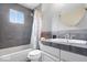 Modern bathroom featuring gray tiled walls, a stylish sink and countertop, a shower, and a large mirror at 5672 W New York St, Indianapolis, IN 46224