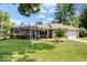 A charming home with a well-manicured front yard featuring a cozy porch and mature trees, showcasing curb appeal at 5672 W New York St, Indianapolis, IN 46224