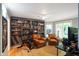 Office space features a grey bookshelf, hardwood floors, leather chairs, and a stationary bike at 5720 Hickory Hollow Dr, Plainfield, IN 46168