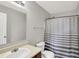 Well-lit bathroom with a large mirror, toilet, and shower with gray striped curtain at 5841 Sable Dr, Indianapolis, IN 46221