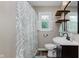 Cozy bathroom with patterned shower curtain and decor shelving above toilet at 6550 Reed Rd, Pittsboro, IN 46167