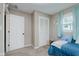 Bright bedroom features neutral walls, carpet flooring, and a window with blue curtains bringing in natural light at 6550 Reed Rd, Pittsboro, IN 46167