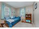 Cozy bedroom features a blue daybed, bookshelves, nautical décor, a window with curtains, and carpet flooring at 6550 Reed Rd, Pittsboro, IN 46167