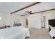 Large primary bedroom with neutral walls, carpet flooring, exposed beams, and a closet, leading to the ensuite bath at 6550 Reed Rd, Pittsboro, IN 46167