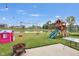 Spacious backyard featuring a playground set, playhouse, lake access, and a fire pit with seating at 757 Carson Ln, Greenfield, IN 46140