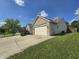 View of the brick home with an attached two-car garage and a well maintained lawn at 8460 Ferguson Cir, Avon, IN 46123