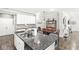 Kitchen with gray countertops, stainless sink, tile backsplash, white cabinets and dining area at 10814 Matherly Way, Noblesville, IN 46060