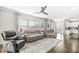 Living room featuring a ceiling fan, three plush seating options, and large windows for natural light at 10814 Matherly Way, Noblesville, IN 46060