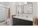 This bathroom has a sleek vanity with double sinks, modern mirrors, and a tiled shower with a curtain at 11315 House St, Indianapolis, IN 46259