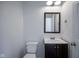 Bathroom with a dark wood vanity, white sink, toilet, and a framed mirror at 12847 Arvada Pl, Fishers, IN 46038