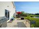 A concrete patio features a grill, outdoor seating, a red umbrella, and a raised garden with a picturesque view of the water at 12847 Arvada Pl, Fishers, IN 46038