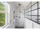 Updated shower features marble tile, a black grid shower door, and a rainfall shower head at 12997 Bartlett Dr, Fishers, IN 46037