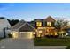 Charming two-story home with a three-car garage, manicured lawn, and inviting front porch at twilight at 12998 Silbury Hill Way, Fishers, IN 46037
