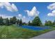 Outdoor basketball court surrounded by well-manicured lawn, trees and blue skies at 13161 Duval Dr, Fishers, IN 46037