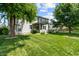 Well-maintained backyard with mature trees, lush green lawn, and covered patio area at 1319 Gable Lake Dr, Brownsburg, IN 46112