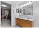 Bathroom featuring a double vanity sink, large mirror, and a door that leads to a large walk-in closet at 1319 Gable Lake Dr, Brownsburg, IN 46112