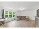 Comfortable living room with wood floors, sectional couch, desk, and a large window with wooded view at 1338 Delacorte Cir, Shelbyville, IN 46176