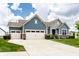 Inviting two-story home boasts a three-car garage, blue siding and a well-manicured lawn at 19009 Beverly Shones Ln, Noblesville, IN 46062